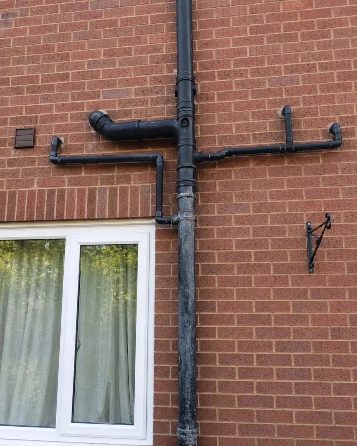 External black soil stack and waste branches installed on a brick wall