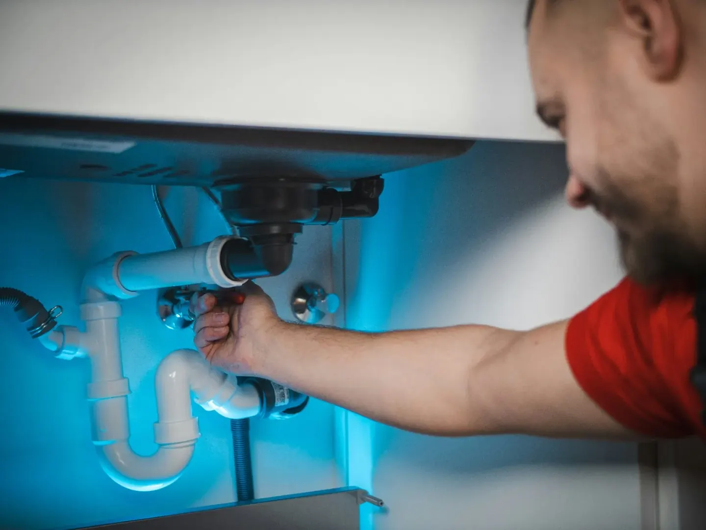 Plumber working below a domestic sink
